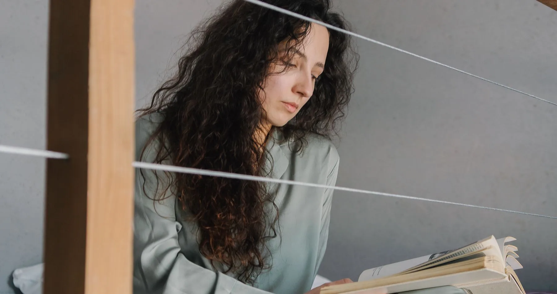 Çatı katı yatak odasında gri pijamayla kitap okuyan bir kadın