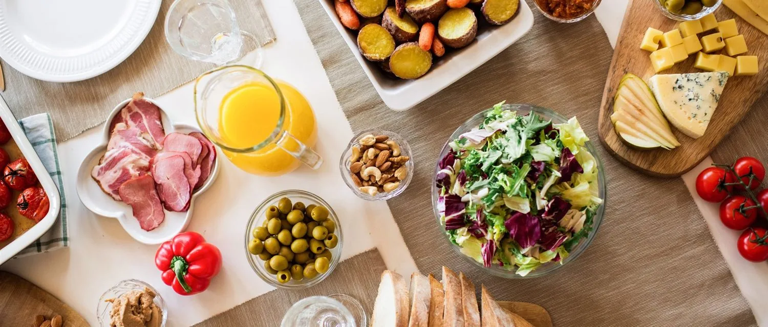 Kahvaltı sofrasında peynir, zeytin, sebze ve fırın ürünleri